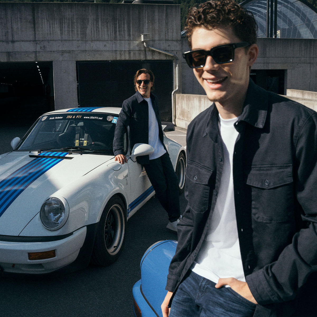 Valentin Kluss and Markus Winkelhock wearing MAC Jeans looks alongside classic sports cars.