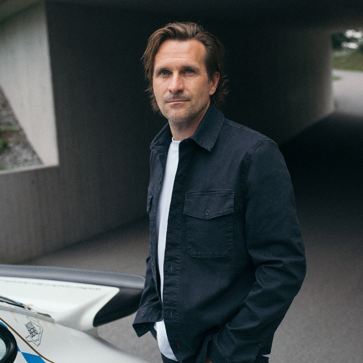 Markus Winkelhock wearing a dark MAC Jeans look beside a classic race car.