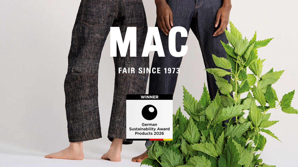 Two models wearing denim jeans with MAC branding and nettle plants, highlighting sustainable fashion.