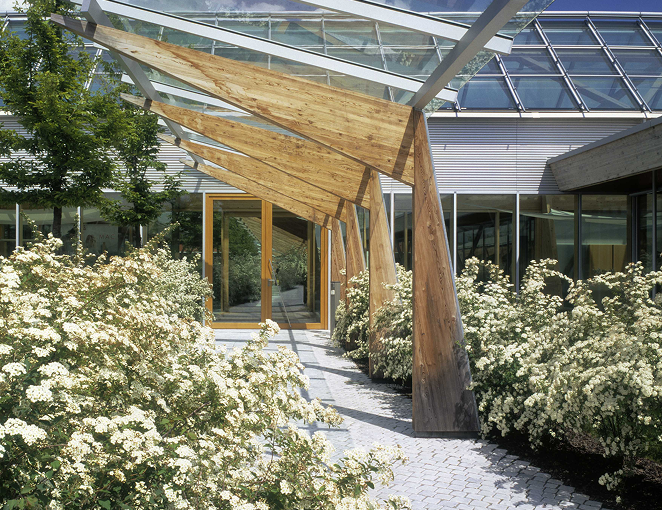 Entrance of the MAC Jeans company building with wooden canopy and greenery.