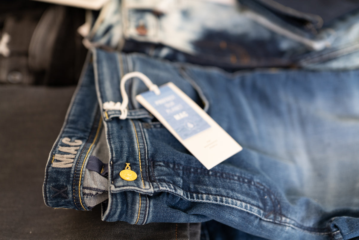 Close-up of folded MAC jeans with branded tag and denim details.