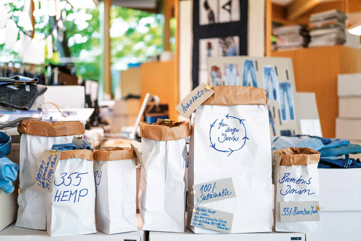 Sustainable denim materials displayed in labeled paper bags at the design studio.