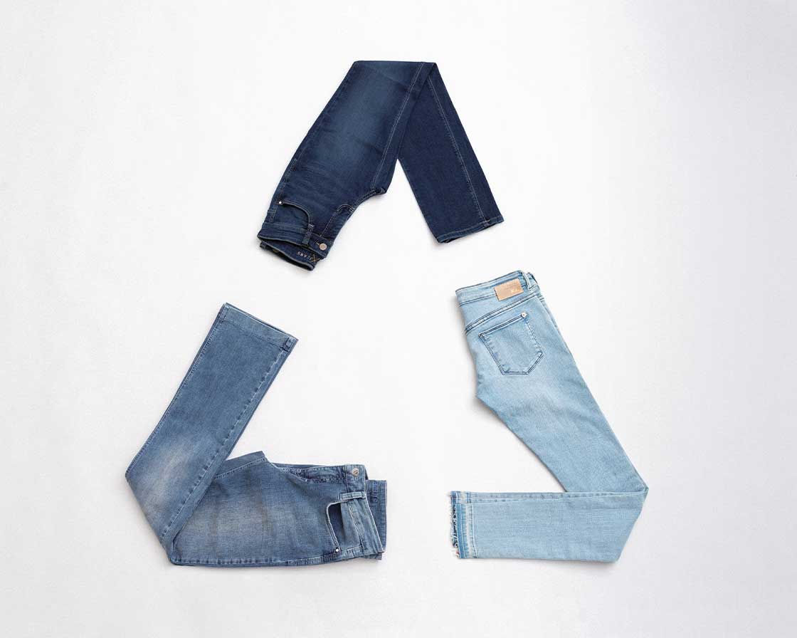 Recycled denim jeans arranged in a circular shape on a light background