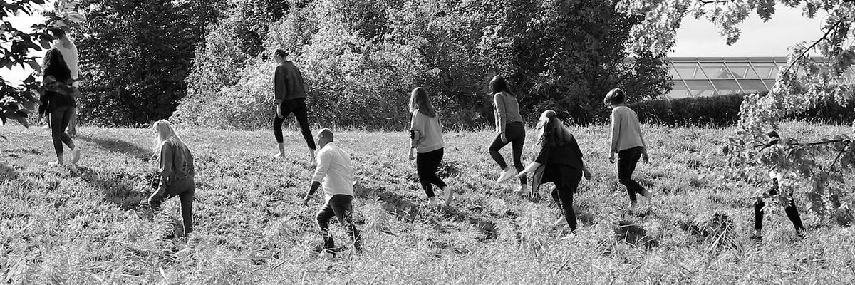 MAC employees walking uphill through a grassy landscape, shown in black and white.