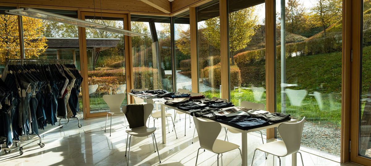 Interior of the MAC headquarters showcasing a bright showroom with denim collections and large glass windows overlooking nature.