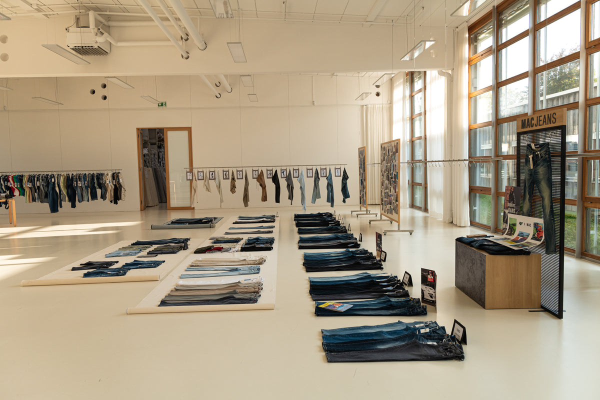 Open showroom displaying MAC denim collections laid out in a modern space.