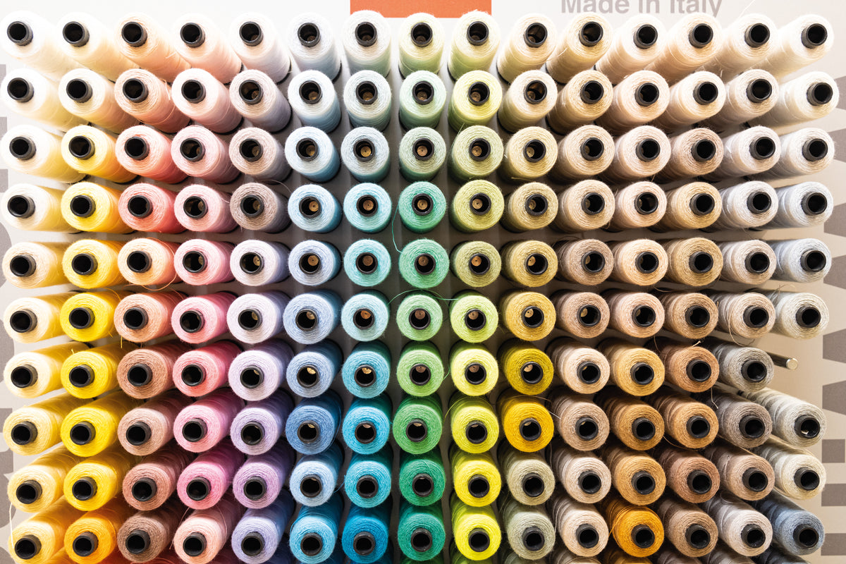 Colorful spools of sewing thread arranged neatly in rows.
